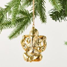 an ornament hanging from a christmas tree decorated with gold ganesha ornaments