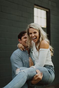 a man holding a woman in his arms while she smiles at the camera and laughs