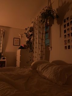 an unmade bed in a dimly lit room with pictures on the wall above it