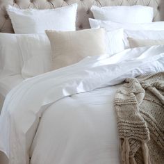 a white bed topped with lots of pillows and blankets