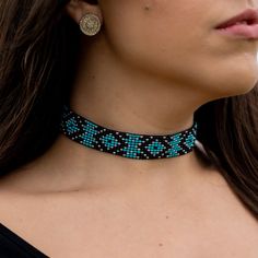 a woman wearing a blue and black beaded choker necklace with matching earring