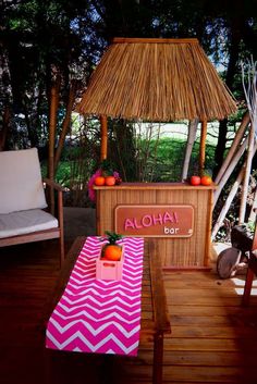 a tiki bar set up on a deck with pink chevron table cloths