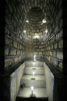 an underground tunnel with stairs lit up at the bottom and light coming from above it