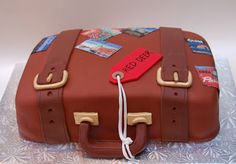 a cake shaped like a brown suitcase with luggage tags on the handle and handles, sitting on top of a silver platter