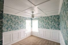 an empty room with floral wallpaper and white trim on the walls is seen in this image