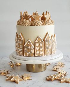 a decorated cake with ginger cookies and icing on a white table next to gold stars