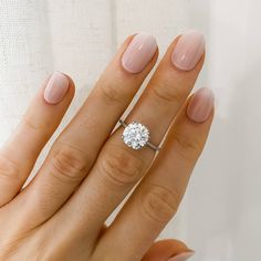 a woman's hand with a diamond ring on her finger and the other hand holding it