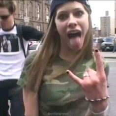 a woman making the vulcan sign while standing in front of a man on a city street