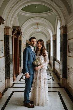 a bride and groom pose for a wedding photo in the hallway of an old building