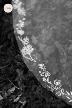 a black and white photo of a cloth with flowers on it, sitting in the grass