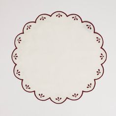 a white doily with red trim on a white background, in the shape of a circle