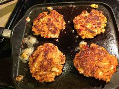 four crab cakes cooking in a cast iron skillet on top of a stovetop