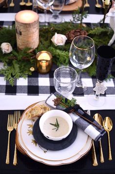 a black and white christmas table setting with goldware, silverware and greenery