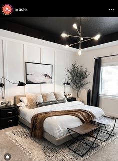 a large white bed sitting in a bedroom next to a black and white rug on top of a wooden floor