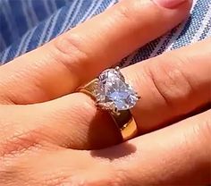 a woman's hand with a ring on it that has a large diamond in the middle