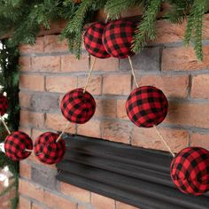 red and black plaid ornaments hanging on a brick fireplace mantel in front of a christmas tree