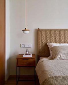 a bed sitting next to a wooden night stand with a lamp on top of it