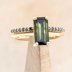 a green tourmaline ring sitting on top of a wooden block