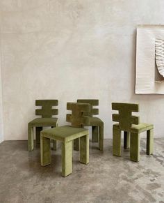 four green chairs and a table in front of a wall with a painting on it