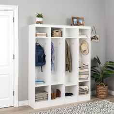 a white bookcase with several coats and shoes on it next to a rug in a room