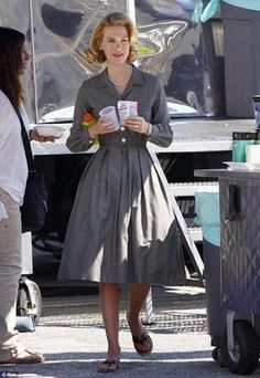 a woman in a gray dress is walking down the street