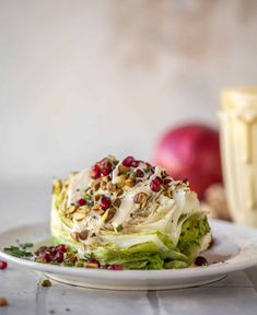 a white plate topped with lettuce and pomegranate covered in dressing