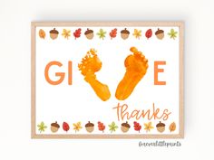 an orange hand and foot print with the words give thanks written on it in front of fall leaves