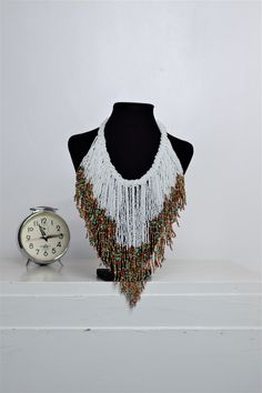 Unique African Maasai Handcrafted Beaded Necklace with an Elegant Look and Brilliant Finish. Circumference = 16 Inches/ 41 Centimeters. Color =White and Multi-Color Maasai Beads. Fringe = 10 Inches / 26 Centimeters. **GET FREE SHIPPING FOR ADDITIONAL ITEMS PURCHASED. Yes, Buy Multiple Items and pay shipping for 1 item only- The rest ships Free. (No Limits on the number of Multiple items). With a faster delivery time of 3 days via DHLExpress, Worldwide. Ordinary/Standard Shipping also available u Bohemian White Jewelry For Festivals, Bohemian White Beaded Necklaces For Festival, White Bohemian Beaded Necklaces For Festival, Bohemian White Necklaces For Festival, Bohemian White Necklace For Festival, Bohemian White Beads For Jewelry Making, White Bohemian Beads For Jewelry Making, Traditional White Beaded Fringe Jewelry, Bohemian White Beaded Necklaces With Dangling Beads