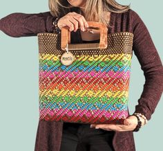 a woman is holding a multicolored bag