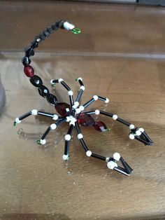 a beaded spider sits on top of a wooden table