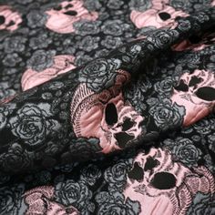 a black and pink skull print fabric with skulls on it's side, as well as roses