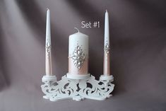 a white candle holder with two candles on it and the number one next to it