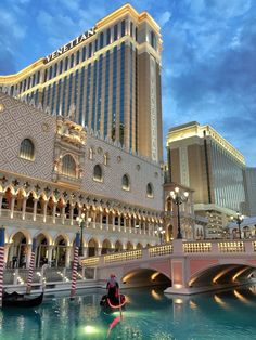 the venetian palace hotel and casino is lit up at night, with a man in a kayak on the water