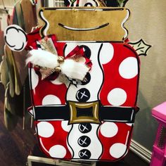 a red and white polka dot purse hanging on a rack in front of a wall