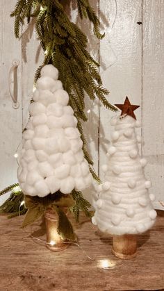 two white christmas trees sitting on top of a wooden table