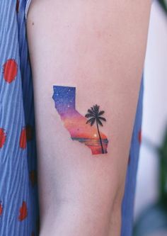 a woman's arm with a palm tree tattoo on it