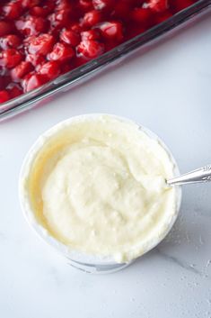 a bowl filled with cream next to a tray of cherries