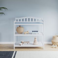 a white shelf with books and toys on it in a blue room next to a potted plant