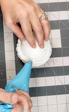 two hands are using a blow dryer on a tiled floor with black and white tiles