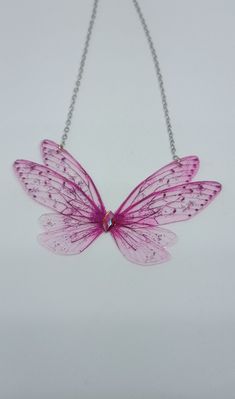 Discover the new magnificent collection of resin fairy wing necklaces. They have been created with love to add a magical and magical touch to your day! *The fairy wing necklace was created by me in my magical workshop. The necklace has a stainless steel chain adjustable by an extension chain. These high-end jewelry pieces are both elegant and durable. *The magical and magical fairy wings are made from resin which is a delicate but sturdy material once hardens. A certain light and shine has been Fairy Wing Necklace, Pink Resin Party Necklaces, Pink Butterfly Necklace For Party, Fairy Style Jewelry With Butterfly Charm For Gift, Handmade Fairy Jewelry For Party, Handmade Fairy Style Jewelry For Parties, Fairy Style Handmade Jewelry For Parties, Handmade Fairycore Necklaces For Party, Handmade Fairy Kei Jewelry For Party