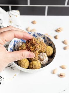 a person is holding something in their hand near a bowl of nuts and almonds