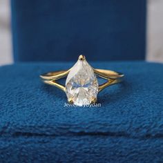 a yellow gold ring with a pear shaped diamond