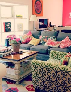 a living room filled with lots of furniture and colorful pillows on top of it's couches