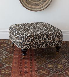 a cheetah print footstool sitting on top of a rug next to a wall