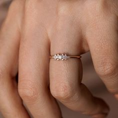 a woman's hand with a three stone ring on her left hand and the other hand holding an engagement ring