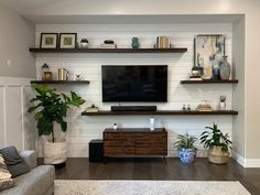 a living room filled with furniture and a flat screen tv mounted on a wall above a wooden entertainment center