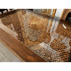 a glass table with lots of brown objects on it's sides and some chairs in the background