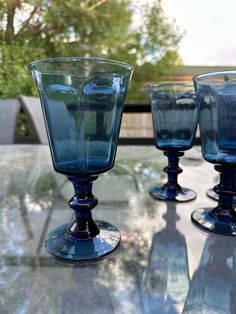 three blue glasses sitting on top of a glass table