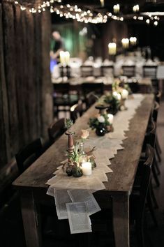 a long table with candles and flowers on it in the middle of a dark room