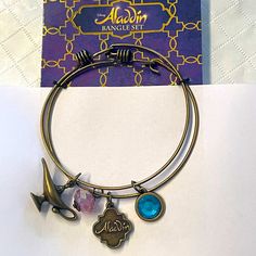 a bangle bracelet with charms on it and a book in the backgroud